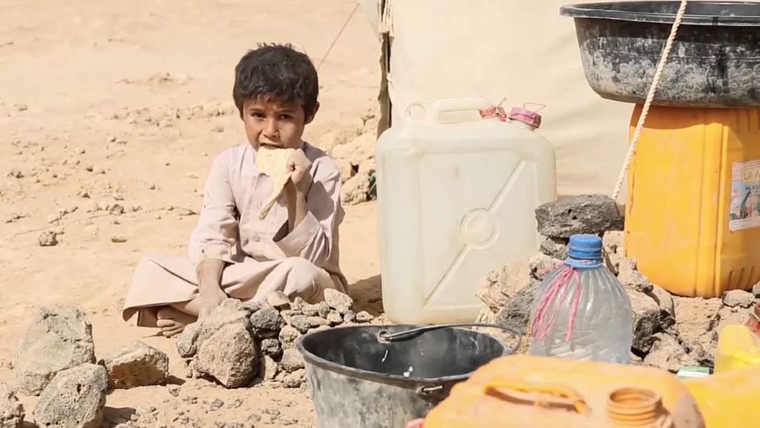 A boy in Yemen sat next to water supplies