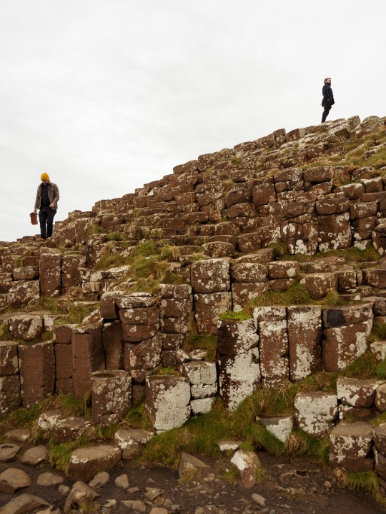 Two men seen climbing over the basalt columns at the Giants Causeway in Northern Ireland