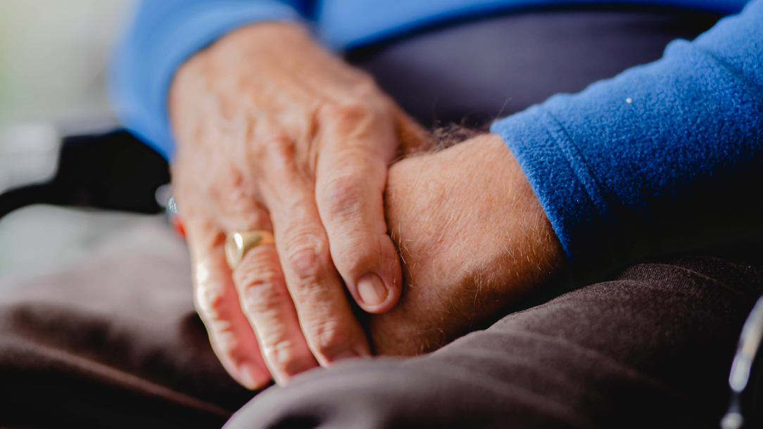 Close up of Graham's hands placed together while he sitting.