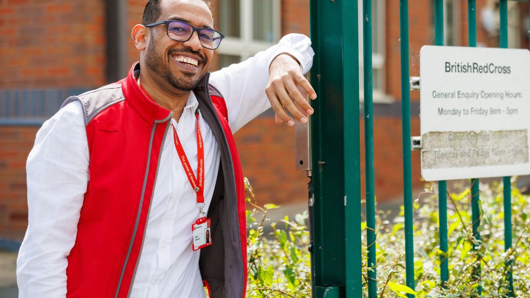 Hatim, a volunteer with the British Red Cross, looks relaxed and smiles at the camera.