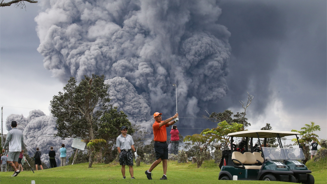 Person playing golf in front of an ash cloud in Hawaii