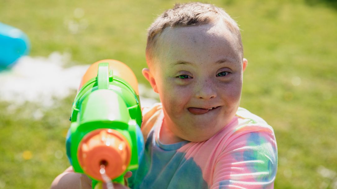 A little boy aims a water pistol at the camera.