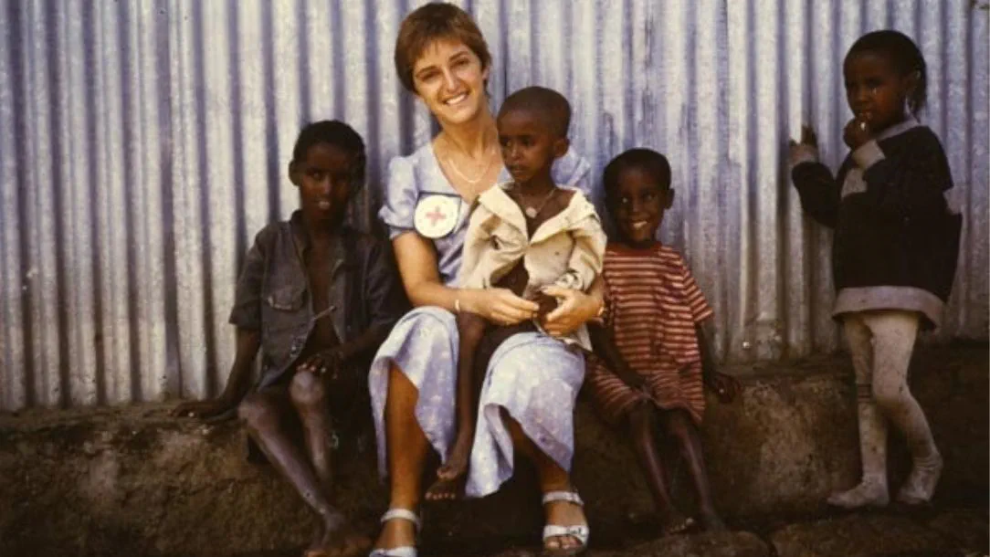 Claire Bertschinger sitting outside a feeding centre surrounded by children.
