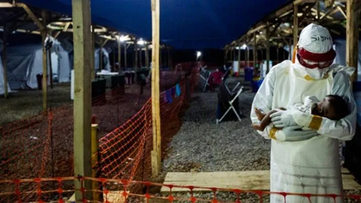 An Ebola nurse in a hazmat suit cradles a tiny baby