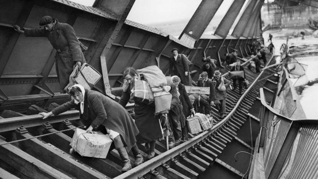 Black and white photo showing people fleeing with their belongings during the war.