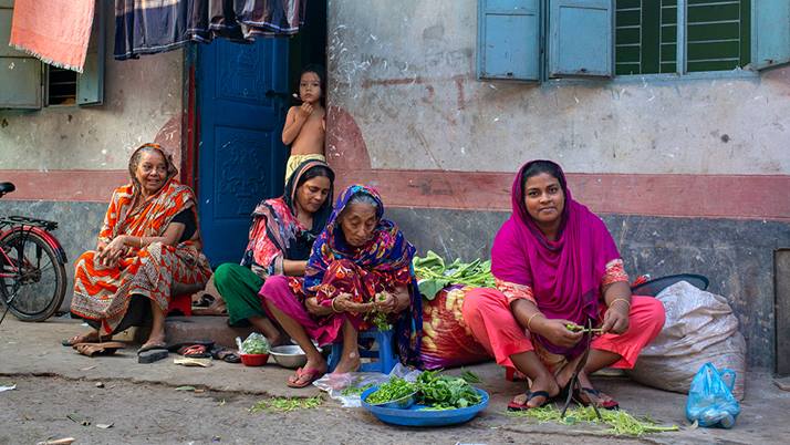 Lima prepares food for her catering business with group of women on street of Barishal, Bangladesh.