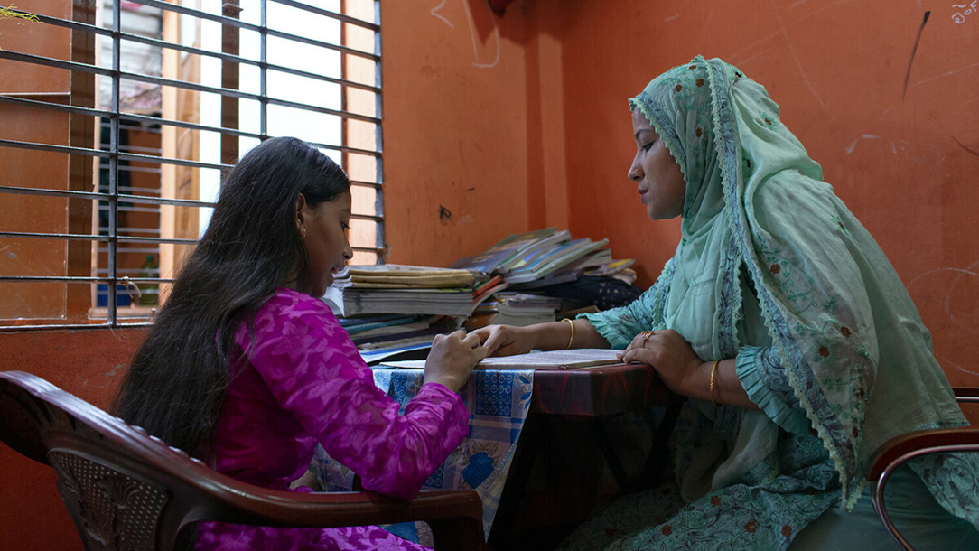 Taslima helps her daughter study in their home in Barishal, Bangladesh.