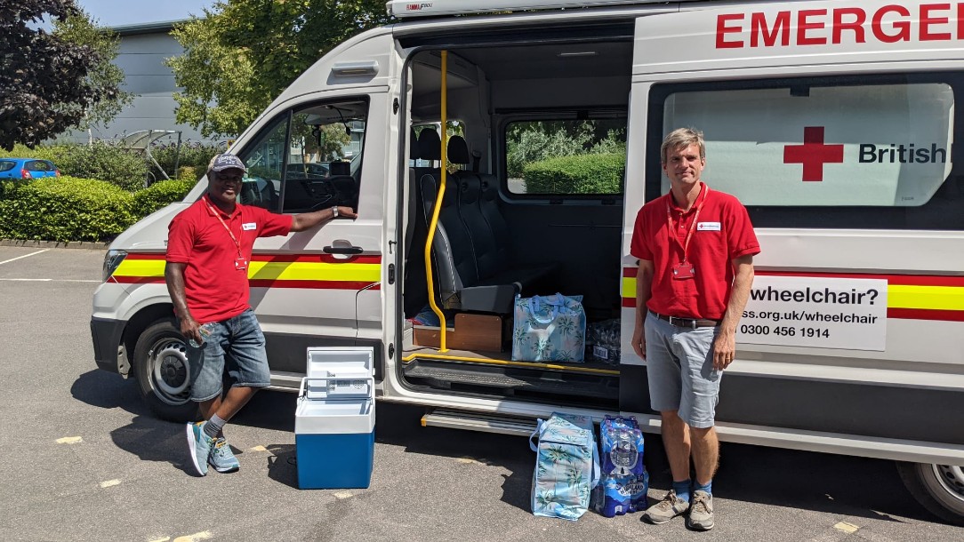 Joe and Tony, two British Red Cross volunteers, stand in front of a Red Cross ambulance armed with refreshments to give to ambulance crews during the UK heatwave.