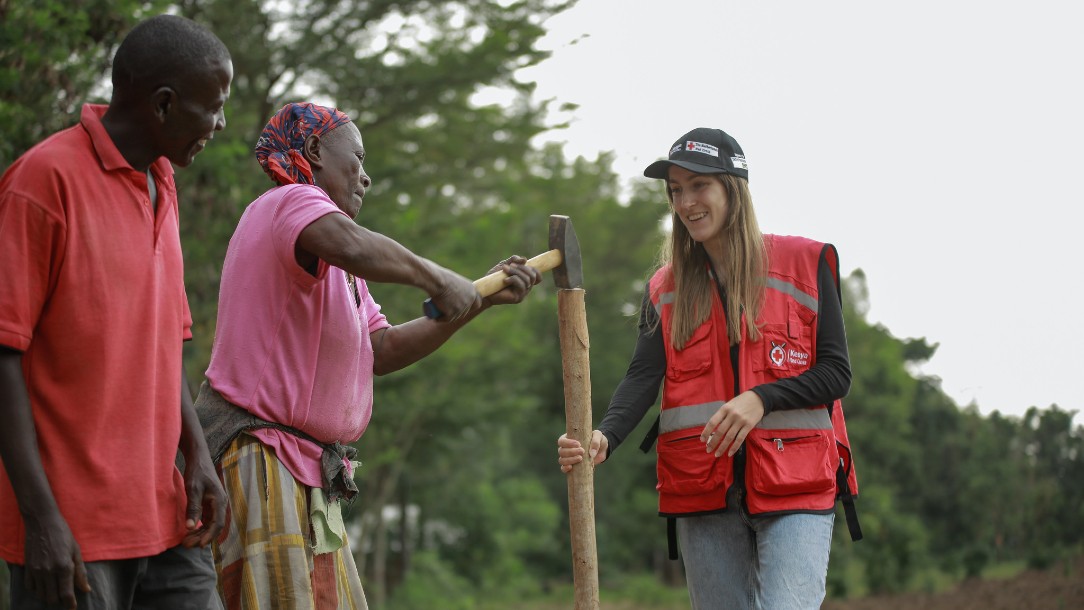 Member of the Kenya Red Cross Society holds a piece of wood as a woman hits it with a hammer as part of a simulation exercise to test early action flood protocols.