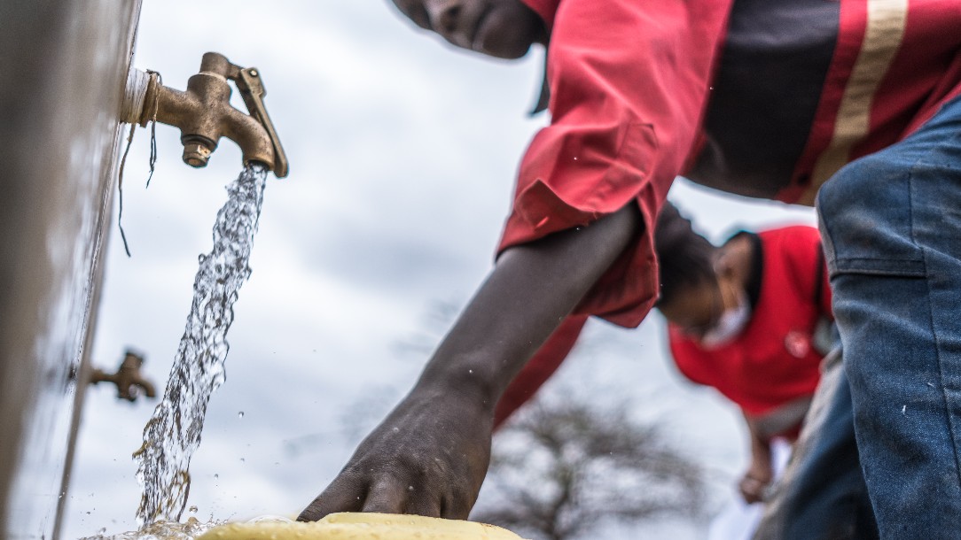 A Red Cross volunteer fills a bucket with water from a tap 