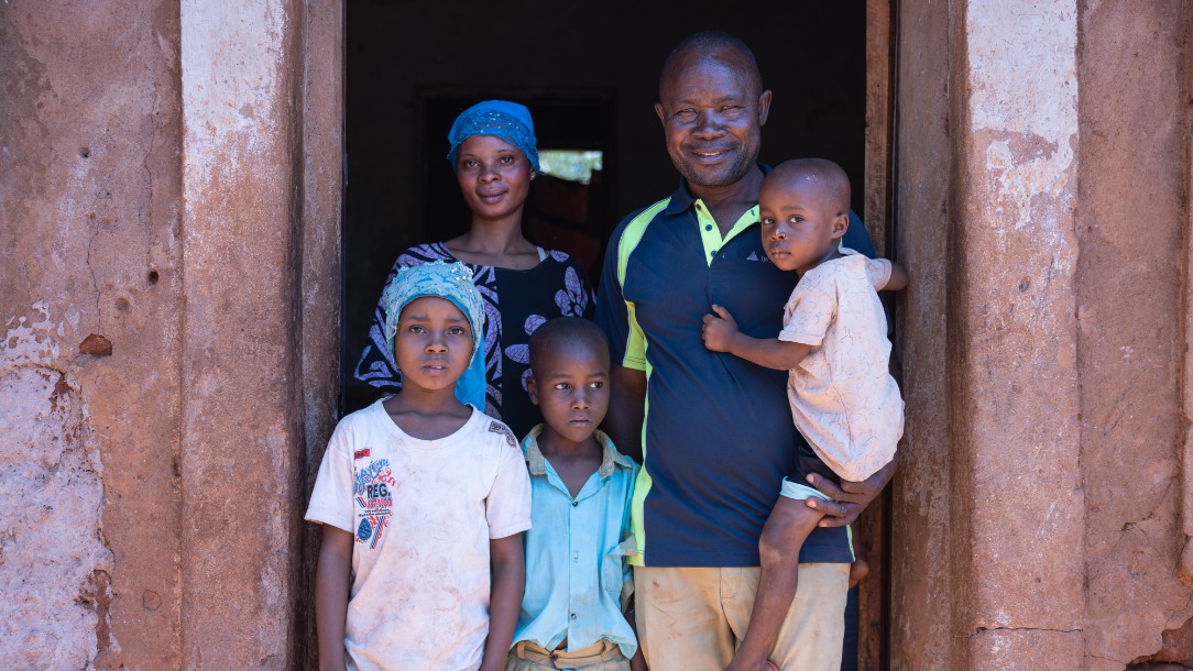 Kizaro, a farmer from Taita Taveta, smiles at the camera, accompanied by his wife and three of their children