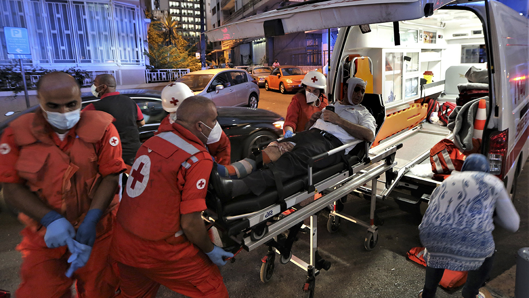 A Lebanese Red Cross ambulance crew put someone in a stretcher into an ambulance.