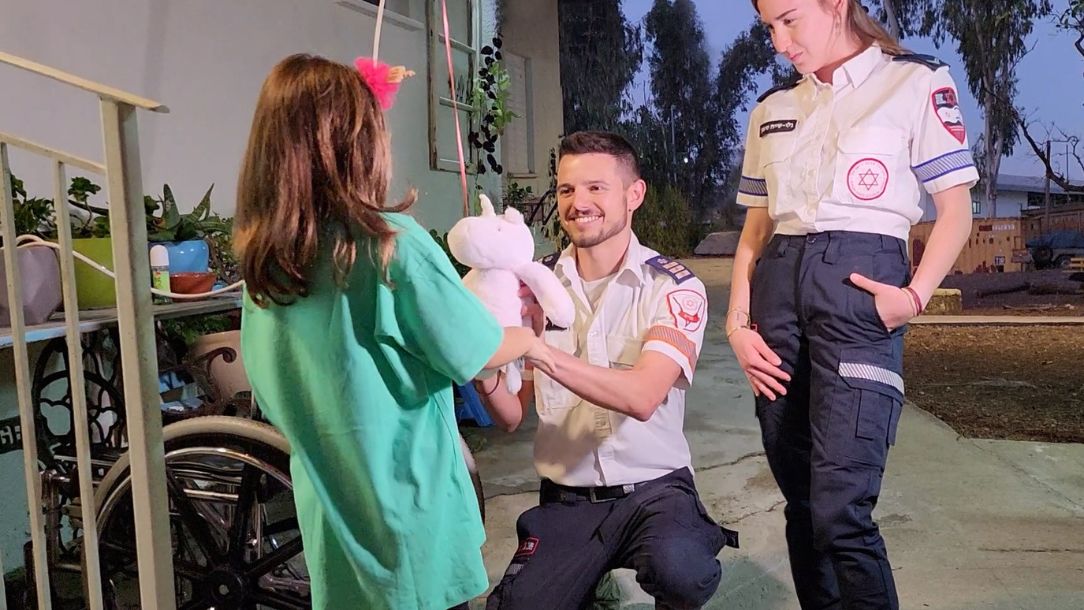 Two MDA responders Yarin and Gali give a teddy bear to a little girl whose life they saved on 7 October in Israel.
