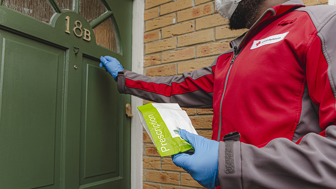 A volunteer drops off a prescription to the home of a person who is self-isolating