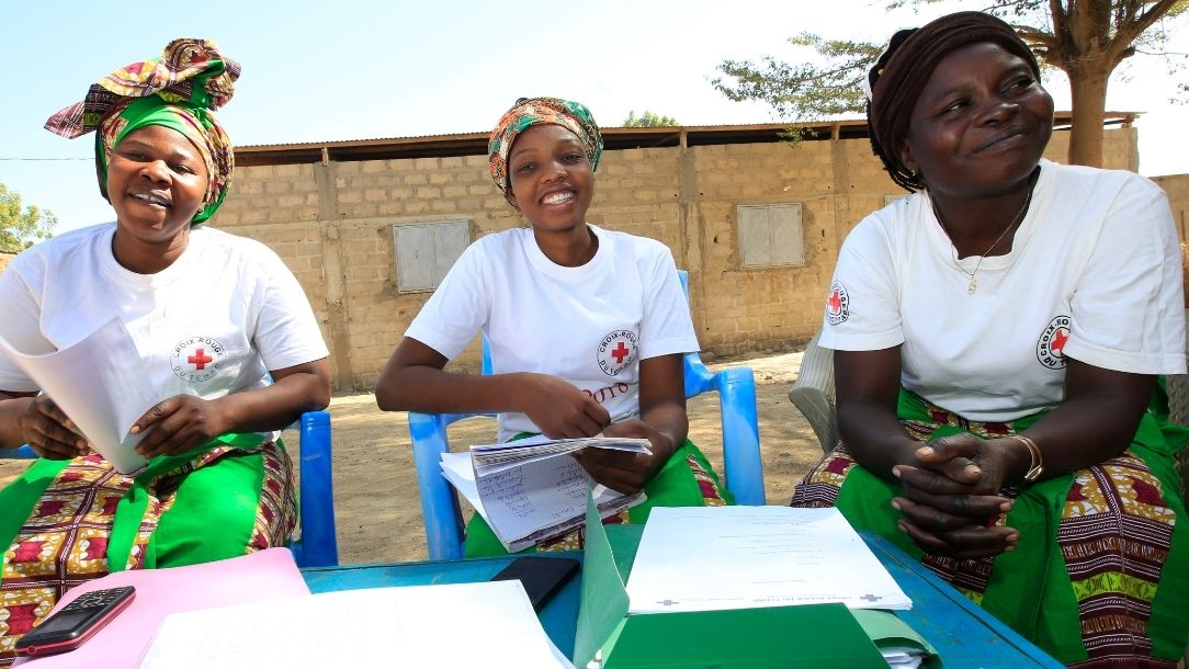 A group of smiling women conduct a mothers' club meets in Chad