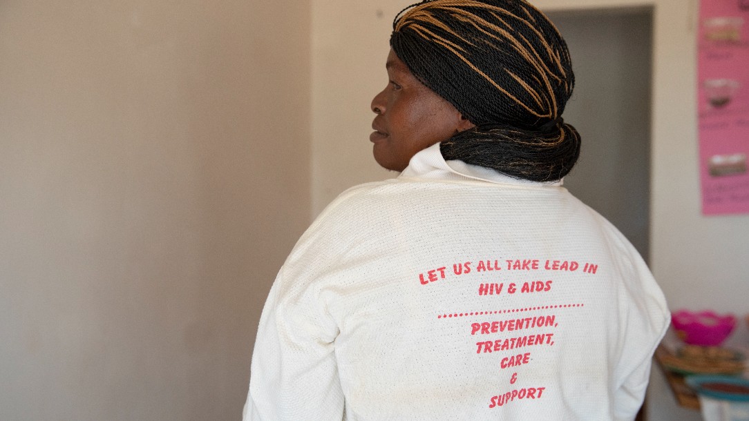 Musa turns her back to the camera to highlight what's written on her -t-shirt. The text reads 'Let us all take lead in HIV and aids'.