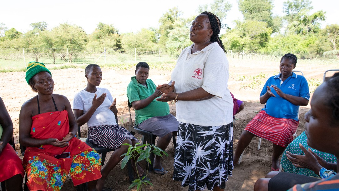 Red Cross volunteer Musa Sibanda with expectant mothers under the tree in the Red Cross nutrition garden