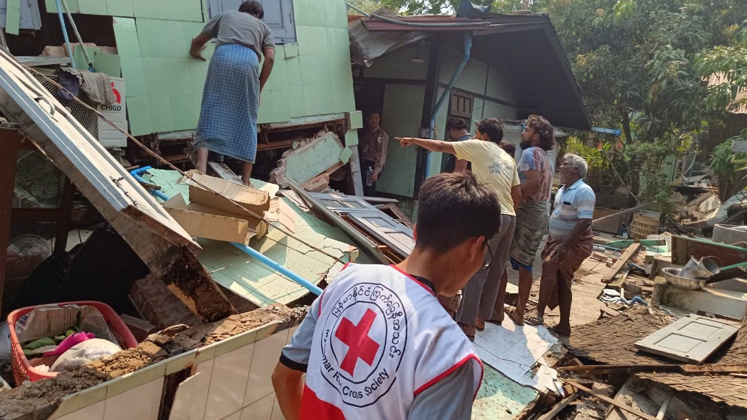 A Myanmar Red Cross volunteer is seen walking through the rubble of a collapsed building