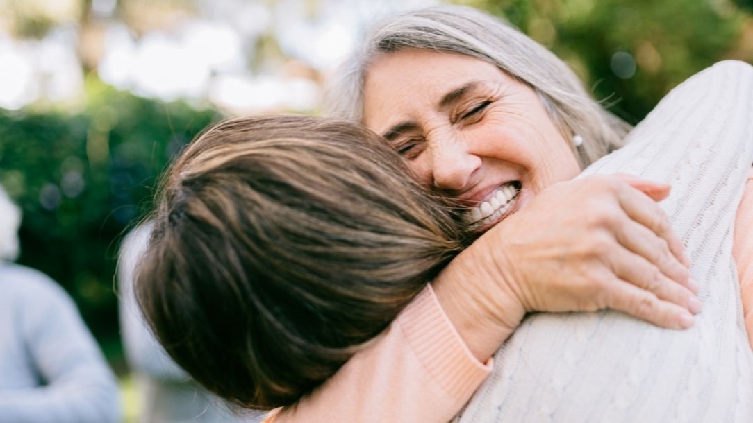 An older woman embraces a younger family member.