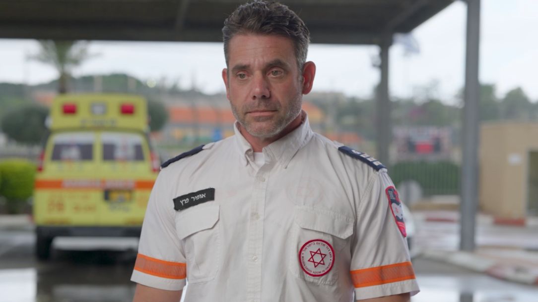 Ofir Peretz MDA ambulance responder, stand in uniform facing the camera and looks sad.