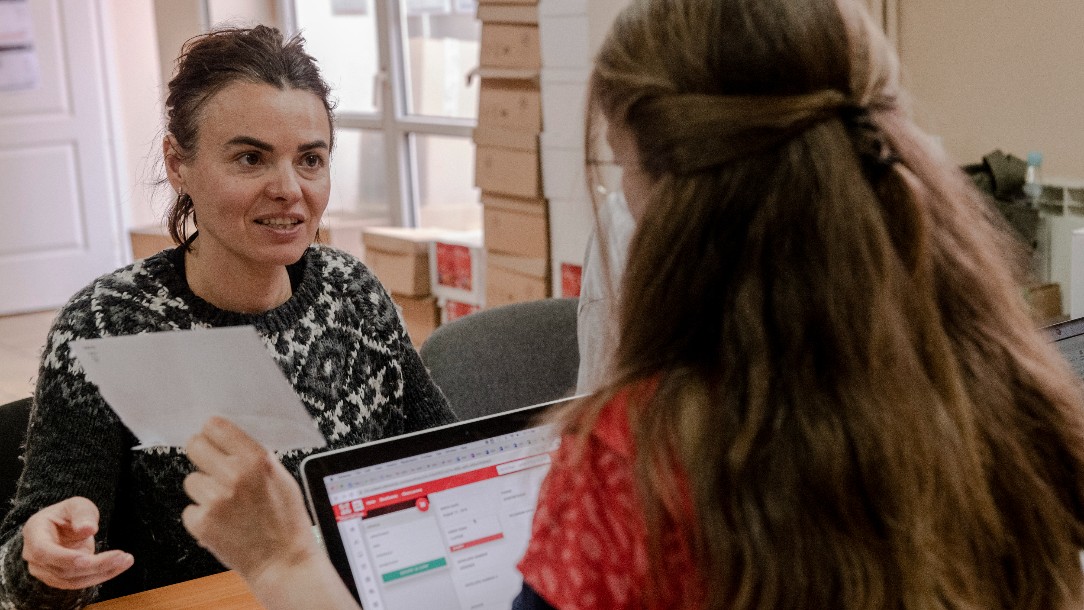 Olena speaks to a member of the Polish Red Cross as she receives a cash card 