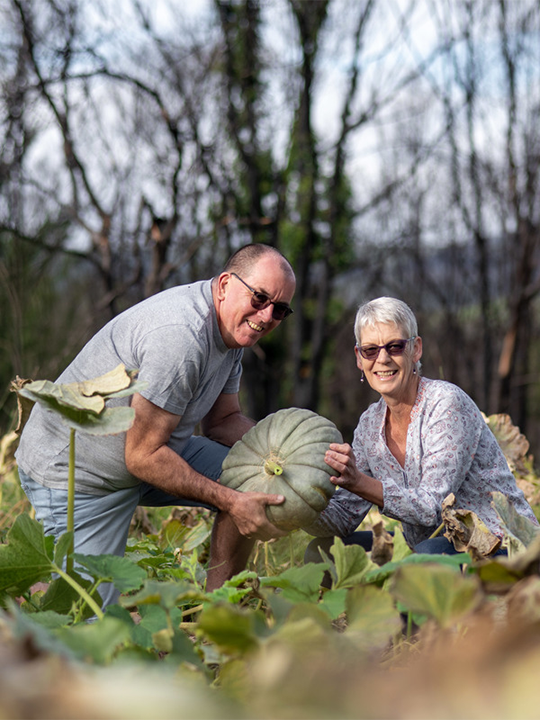 Norelle and David, who got a grant from the Red Cross after the Australian bush fires, hold a squash in their new garden.