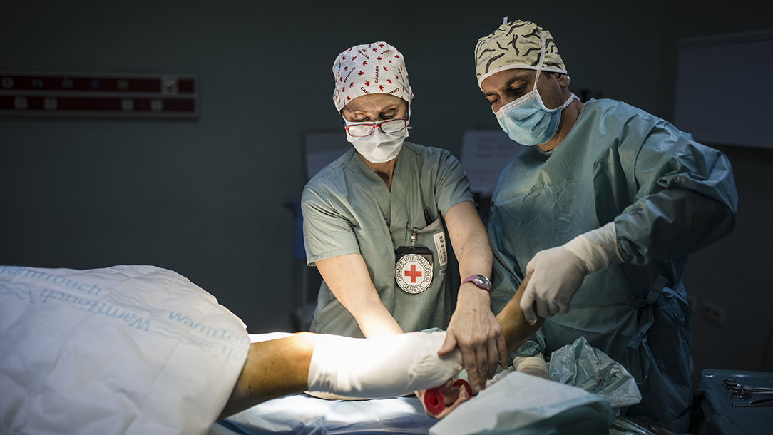 An operating theatre nurse wearing a uniform bearing the red cross emblem puts a bandage on the operated wounds of a patient who was injured in Mosul.