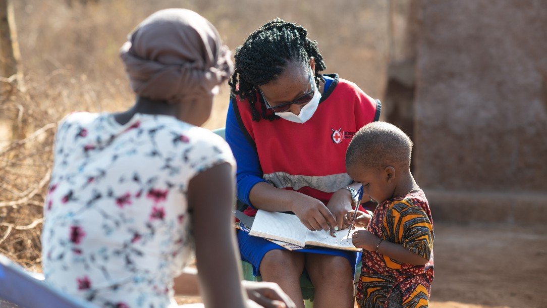 Evelyn, a project officer from the Kenyan Red Cross plays with Agnes's son Jacob on a home visit in Taita Taveta county, Kenya