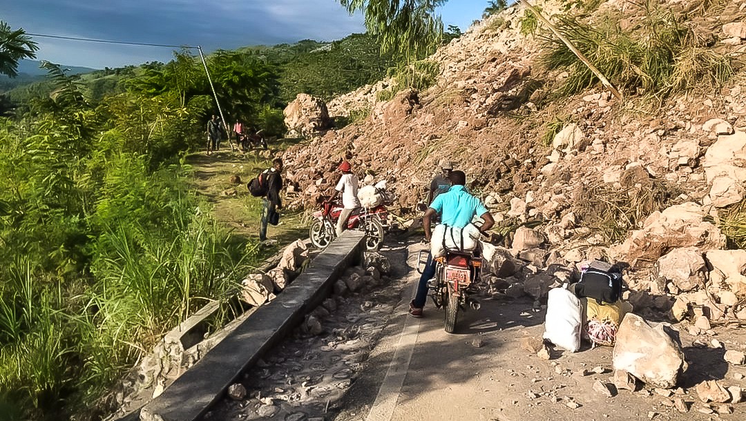 A man on a motorcycle tries to navigate a rubble-strewn road in the aftermath of the earthquake in Haiti