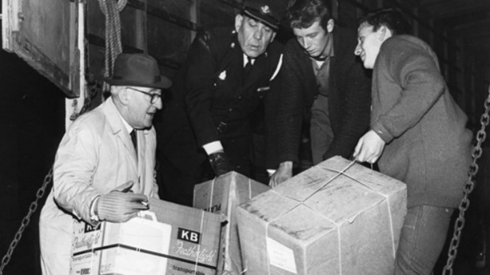 Two police officers and two other men lift cardboard boxes into the back of a van at the time of the mining disaster in Aberfan.