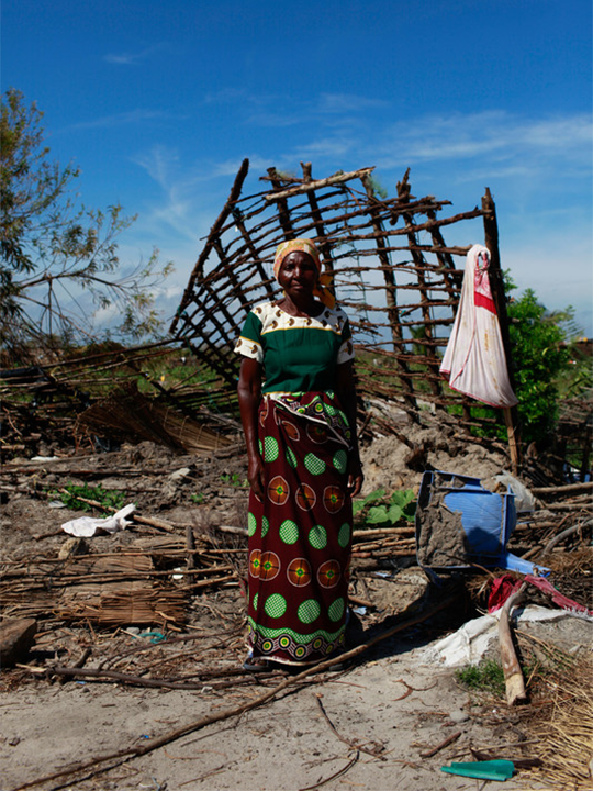 A woman in Mozambique stands in the ruins of her home, which was destroyed by a cyclone.