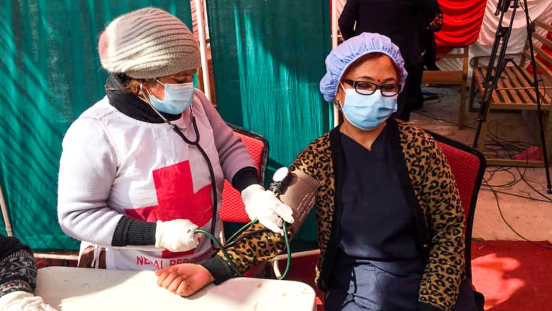 A woman receives her Covid-19 vaccination from a Red Cross staff member, in Nepal 