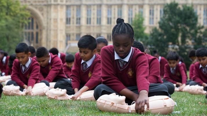 Children from Ark Oval Primary Academy School in South London practise first aid on dummies on the lawn in front of the UK Houses of Parliament.