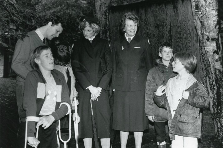 Princess Diana stands with a group of volunteers and children at a British Red Cross camp.