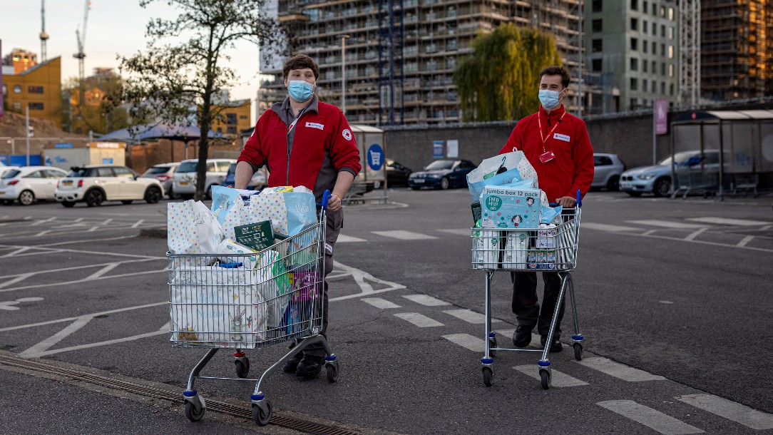 Two British Red Cross volunteers push trollies filled with items for the evacuated residents of the building in Poplar