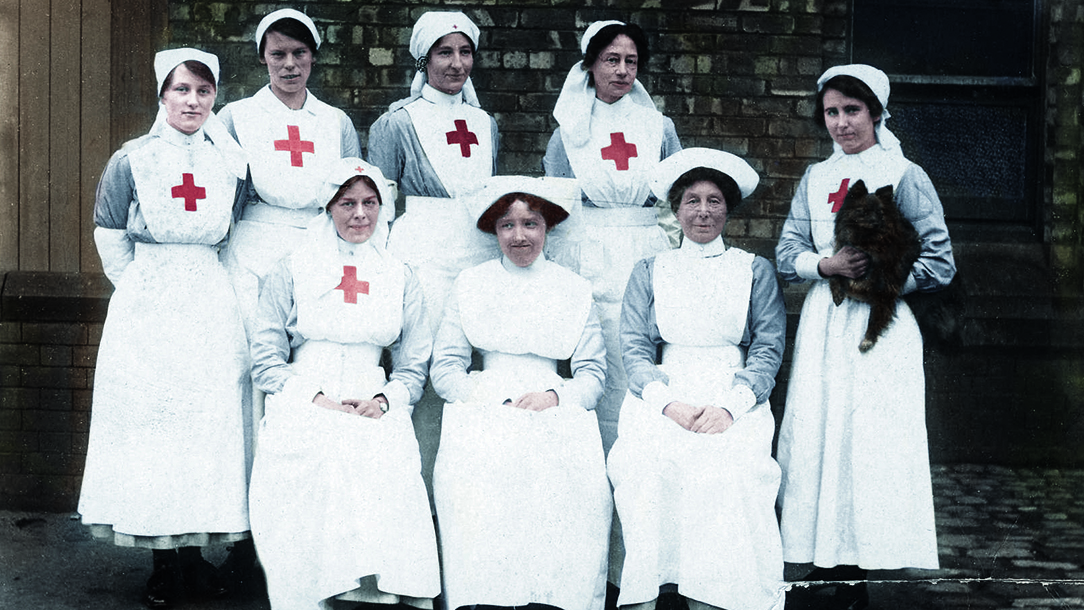 A group of WWI Red Cross volunteer nurses are seen in their uniforms, which show a large red cross emblem on the fronts