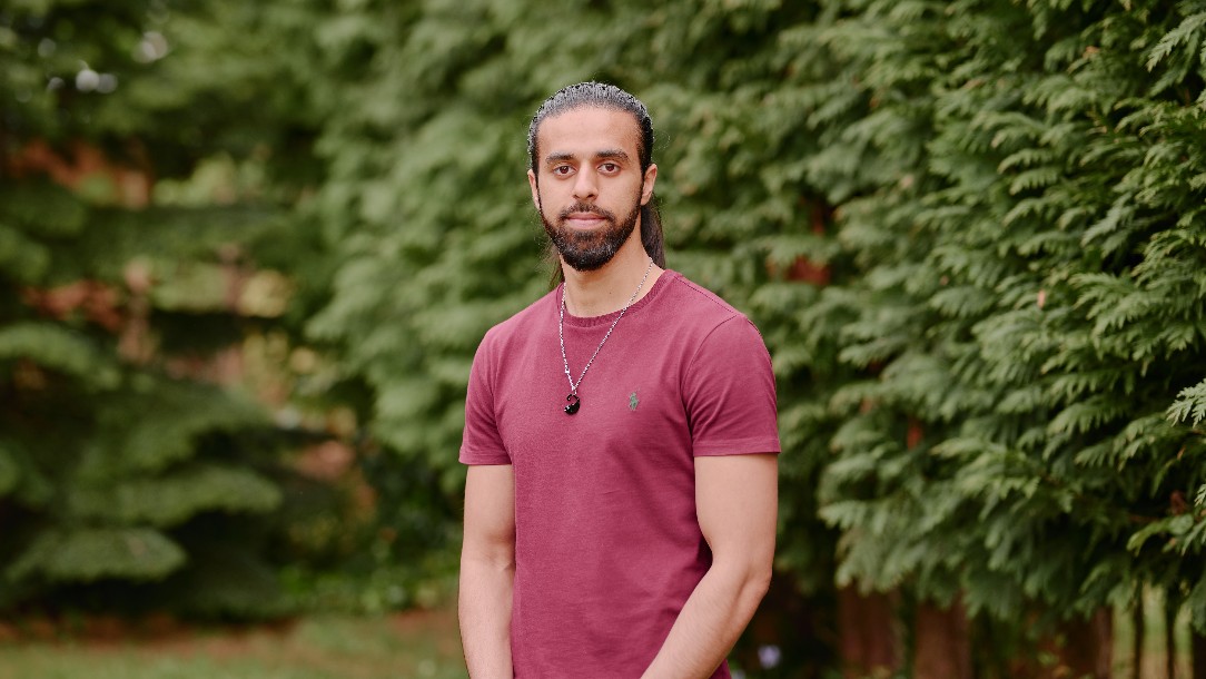 Zain, one of the VOICES ambassadors who appears in the podcast, stands outside looking toward the camera