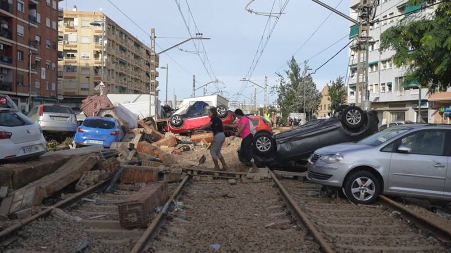 People pushing cars on train tracks