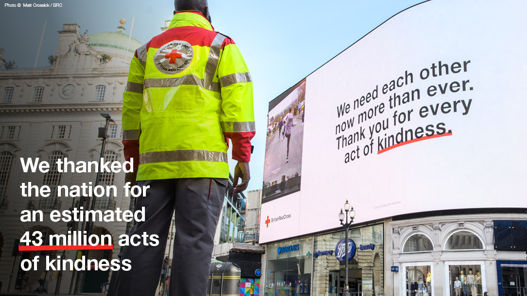 Volunteer looks up at the British Red Cross billboard in Piccadilly Circus.