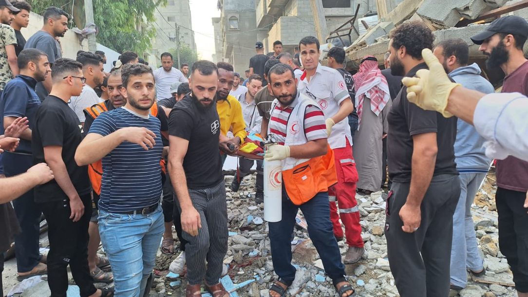 Teams from the Palestine Red Crescent support people affected by the crisis in Israel and Gaza, supported by a crowd of people in need of support.