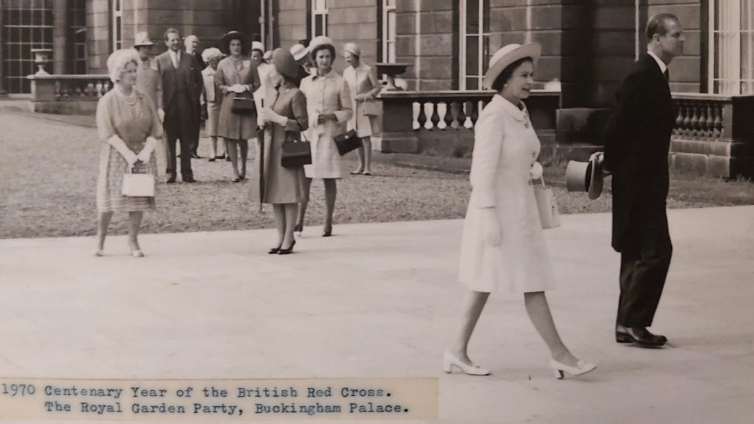 A black and white photograph showing the Queen walking to a garden party at Buckingham Palace to celebrate the British Red Cross centenary.