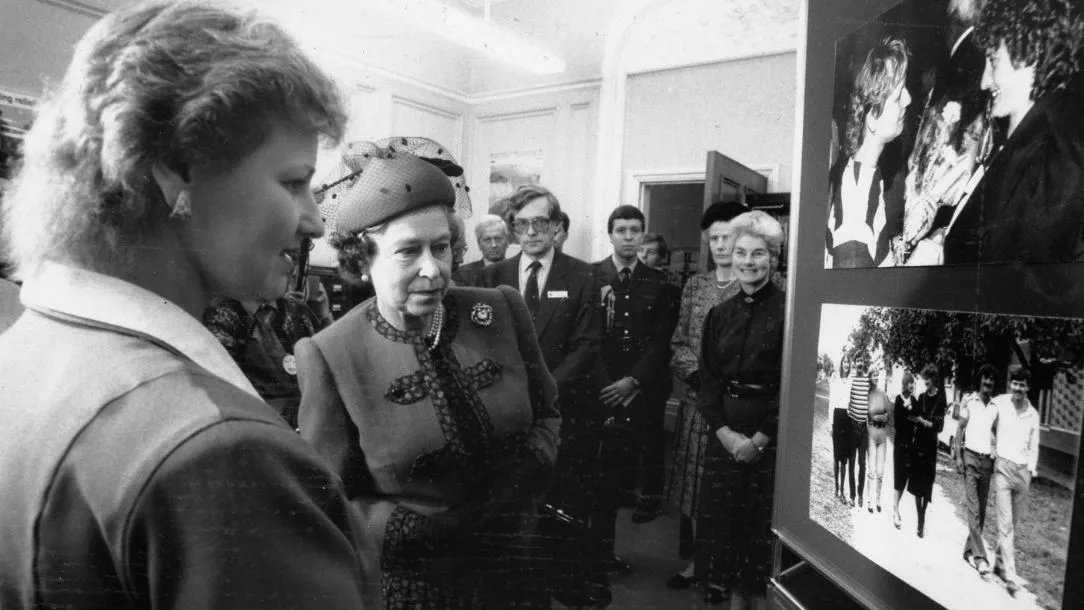 A black and white photograph showing the Queen visiting the British Red Cross HQ for the first time in 1989.
