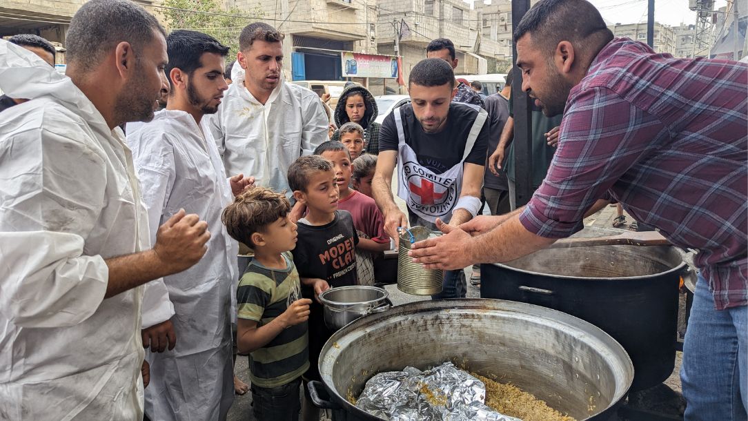 The Palestine Red Crescent gives hot food to a crowd of men, women and children in Gaza.