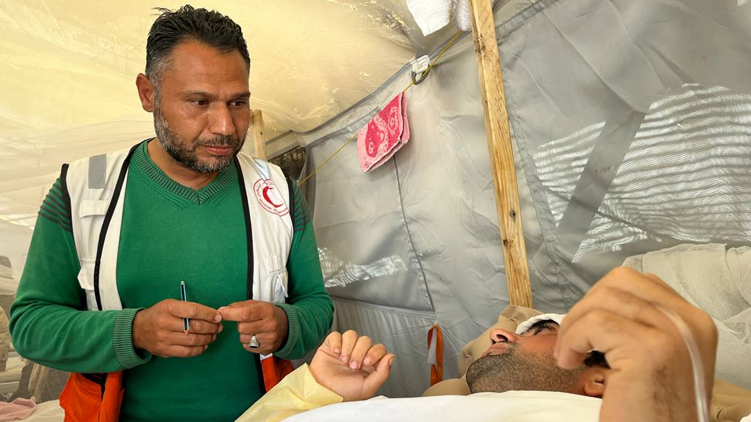 A specialist attends a wounded person on a bed at a Red Cross Field Hospital in Rafah.