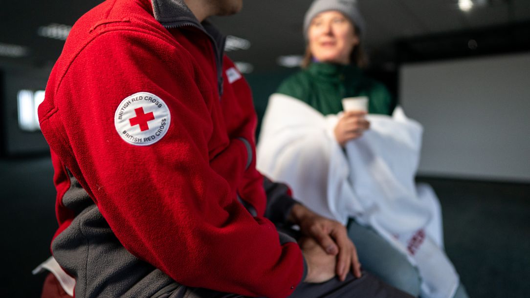 A British Red Cross volunteer speaks to a volunteer at a rest centre.