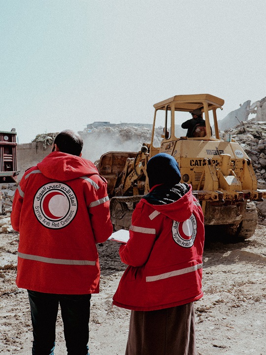 A photo of two Syrian Red Crescent staff surveying damage earthquake in Aleppo.