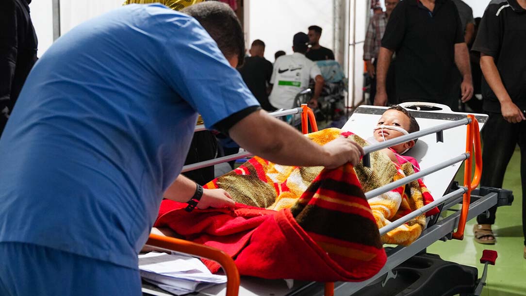 A doctor wearing scrubs pushes a young boy on a stretcher with an oxygen tube in his nose at the Palestine Red Crescent medical centre in Gaza.