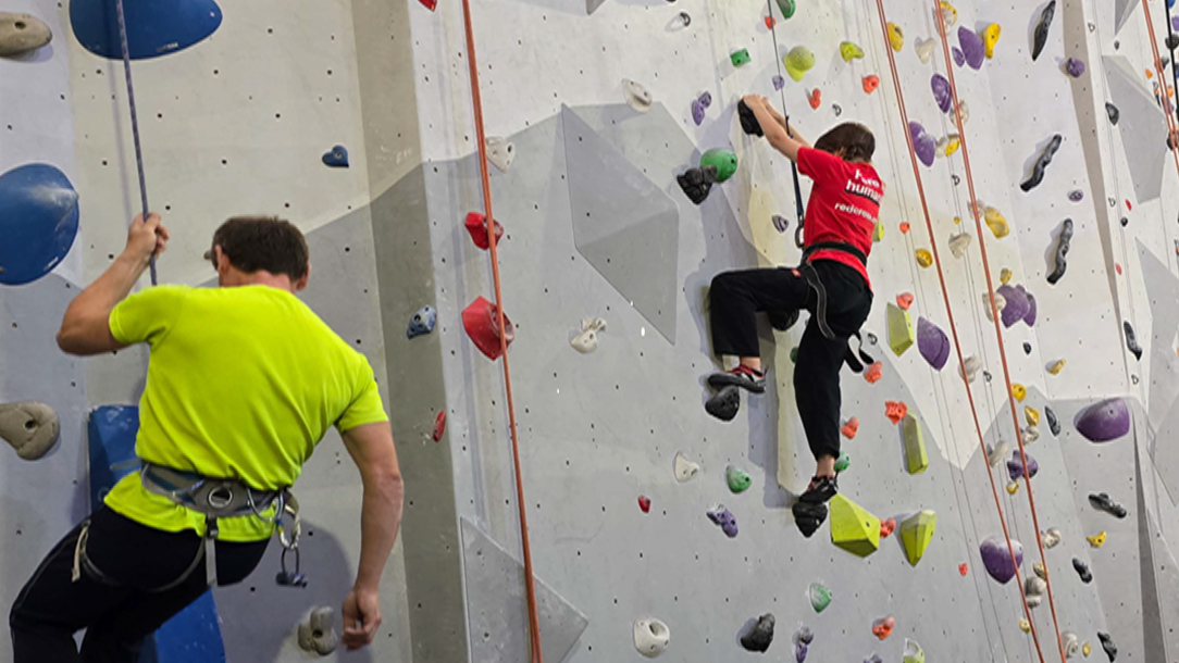 Two people on a climbing wall with ropes.