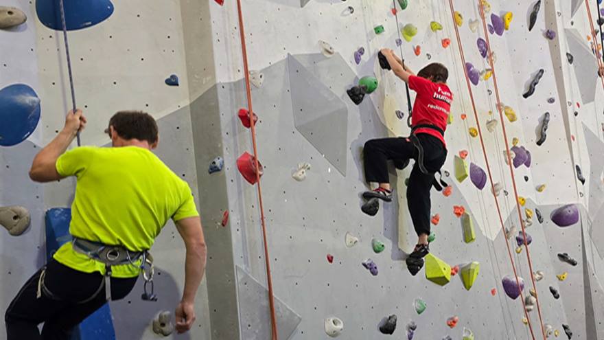 Two people on a climbing wall with ropes.