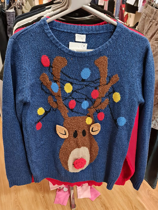 A Christmas jumper with embroidery of a reindeer hangs in a British Red Cross charity shop.